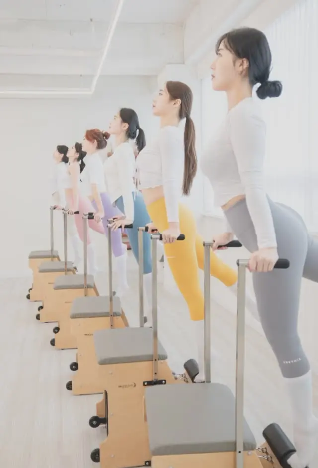 회원들이 체어 기구 위에서 동작을 따라 하는 수업 장면